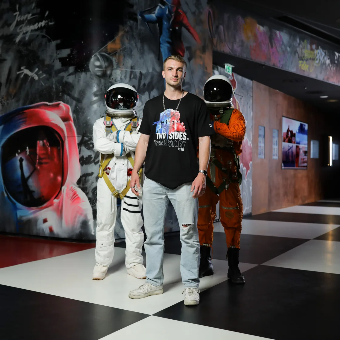 A picture shows a young stylish man in front of two Astrunauts in the Cold War Museum Berlin.