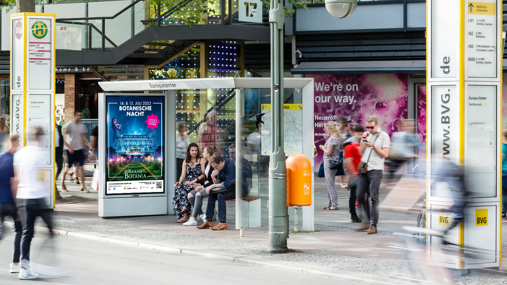 A picture shows a bus stop with a poster for Botanical Night in the Botanical Garden Berlin.