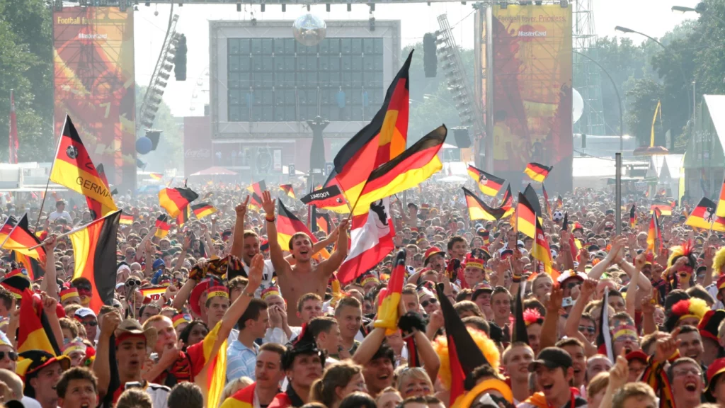 Ein Bild zeigt Fans mit Fahnen beim feiern der deutschen Nationalmannschaft bei "Die Meile" am Brandenburger Tor in Berlin.