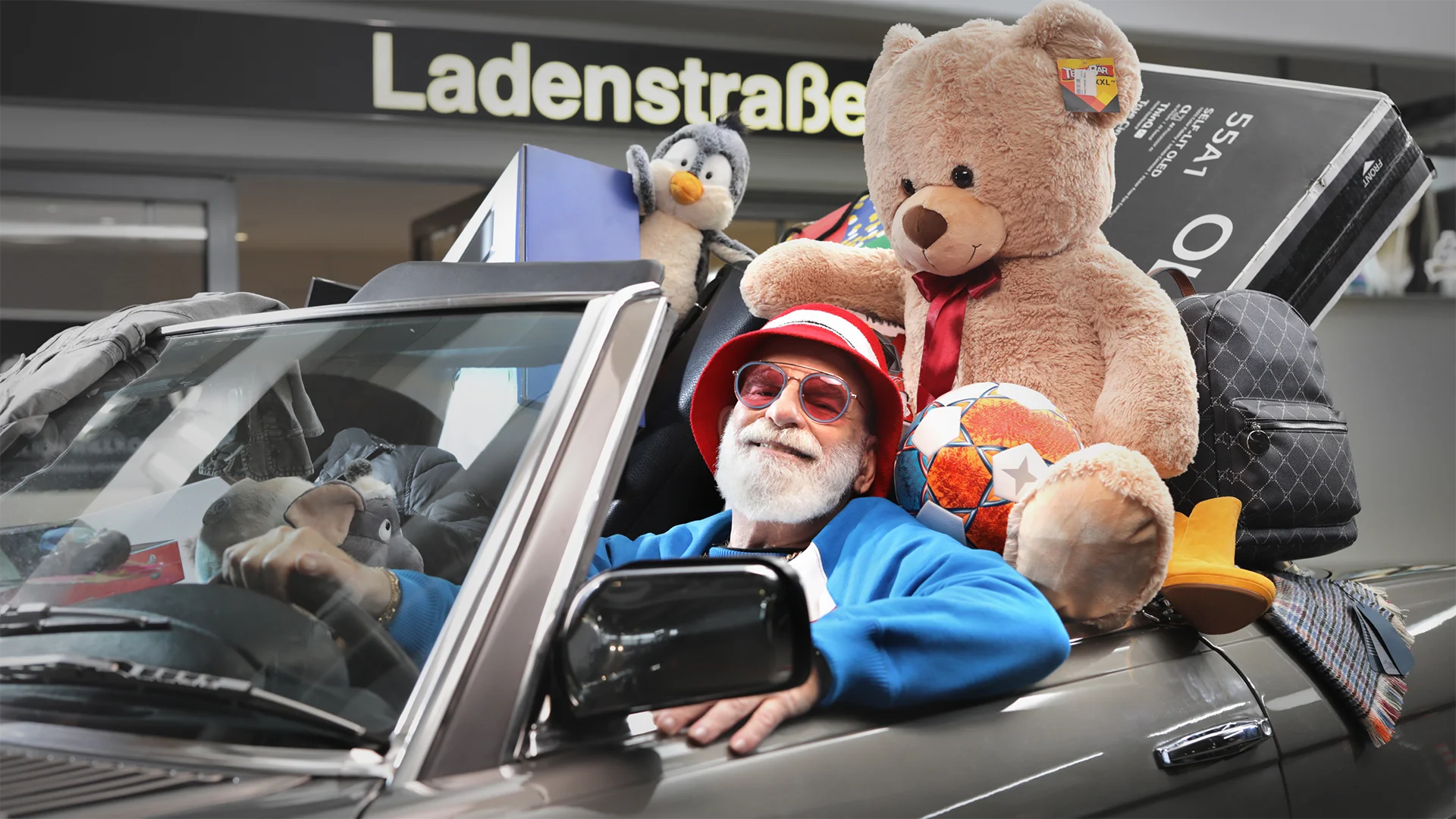 One picture shows a man in a convertible with lots of shopping for the subject 